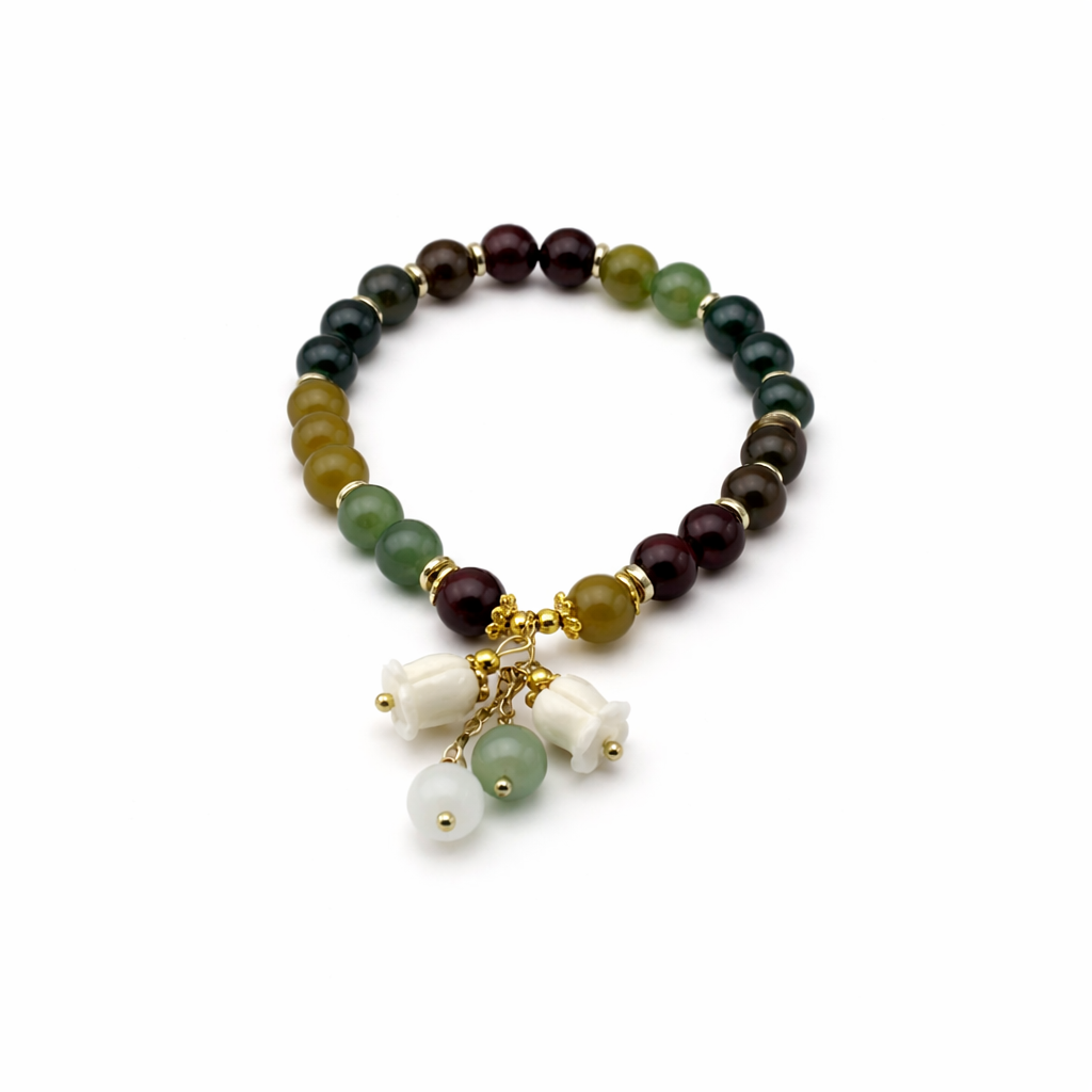 Beaded bracelet with gold charm and white beads on a white background