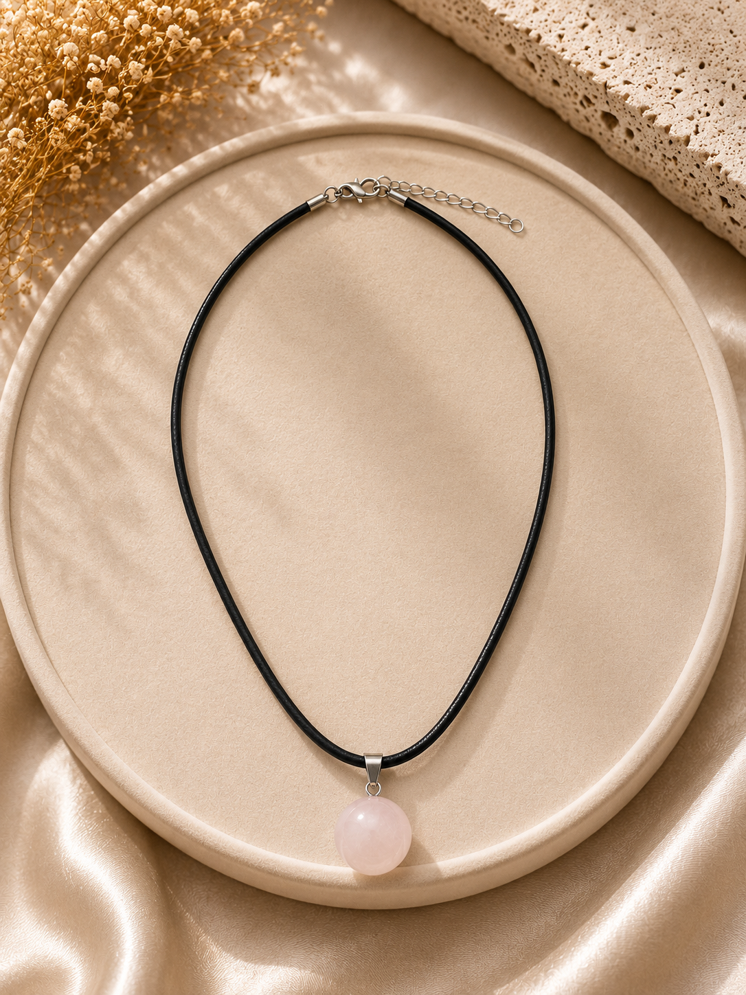 Necklace with a pink pendant on a beige plate
