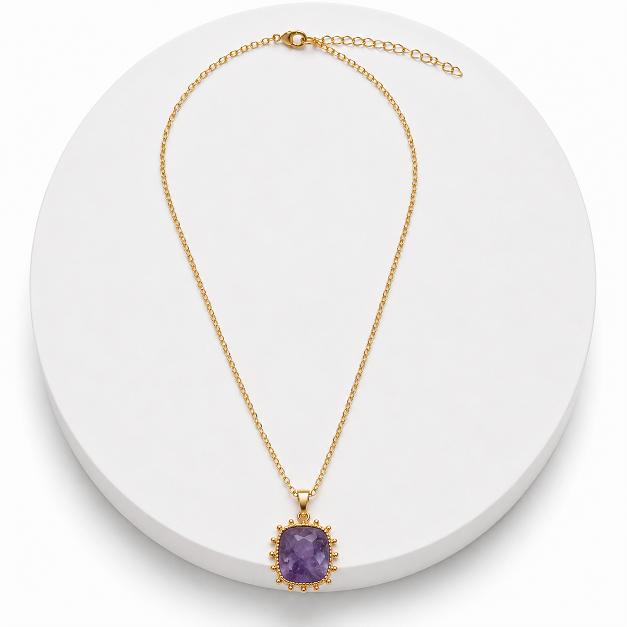 Gold necklace with a purple pendant on a white background