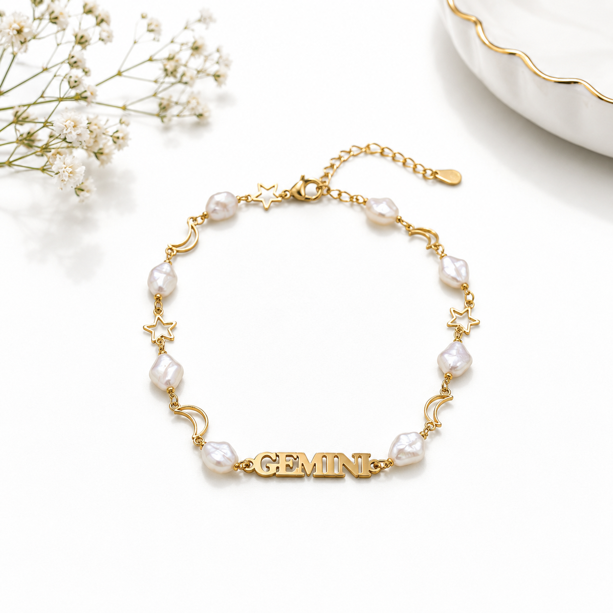 Gold bracelet with pearl beads and 'GEMINI' charm on a white background