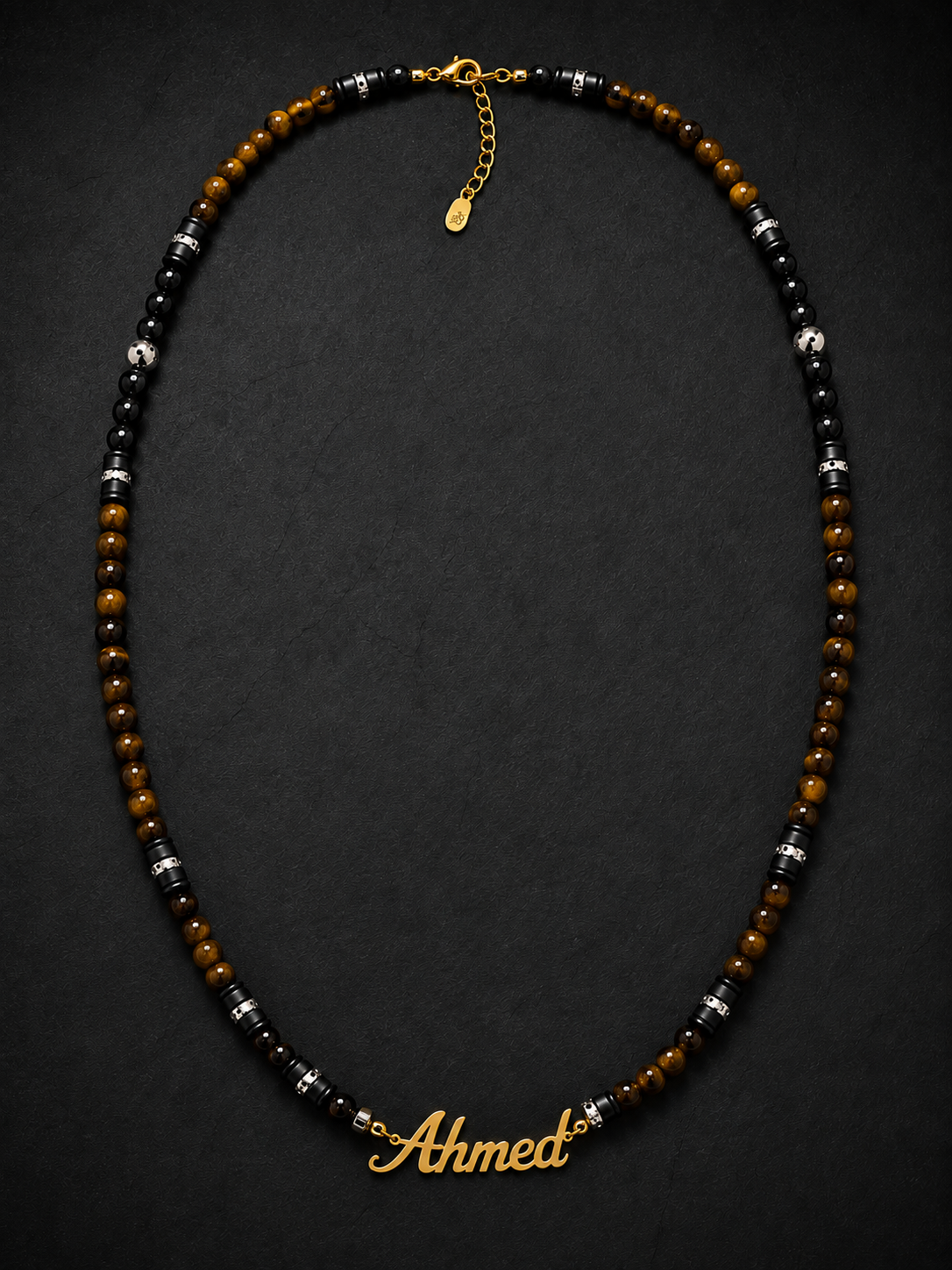 Necklace with beads and a gold nameplate 'Ahmet' on a dark background