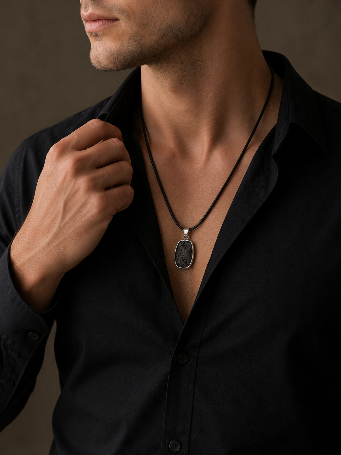 Man wearing a black shirt with a necklace against a brown background
