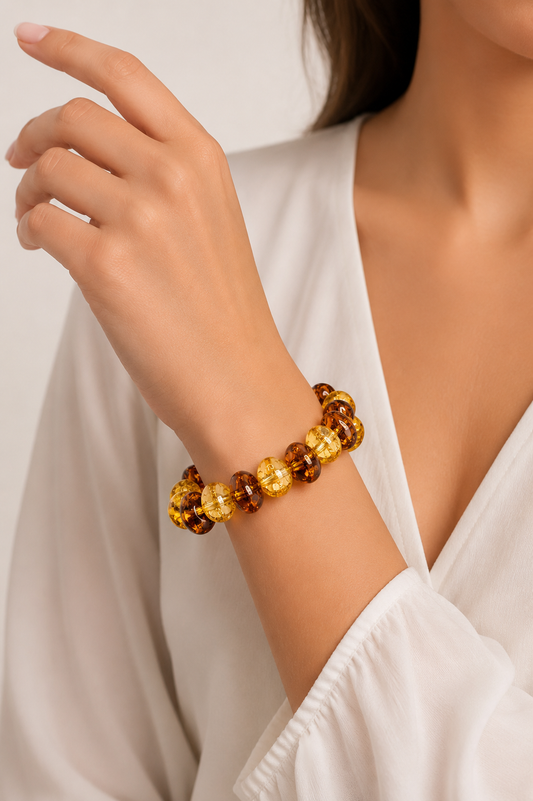 Close-up of a woman's arm wearing a brown and gold beaded bracelet against a neutral background