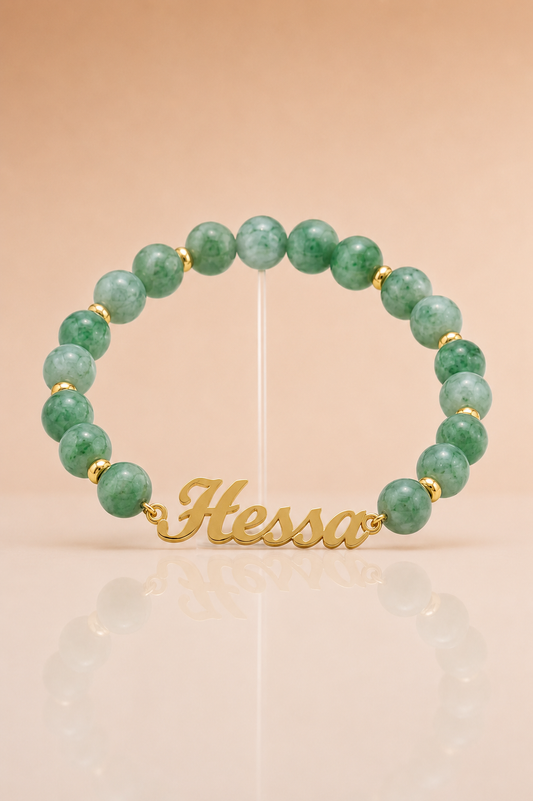 Green beaded bracelet with gold accents on a beige background