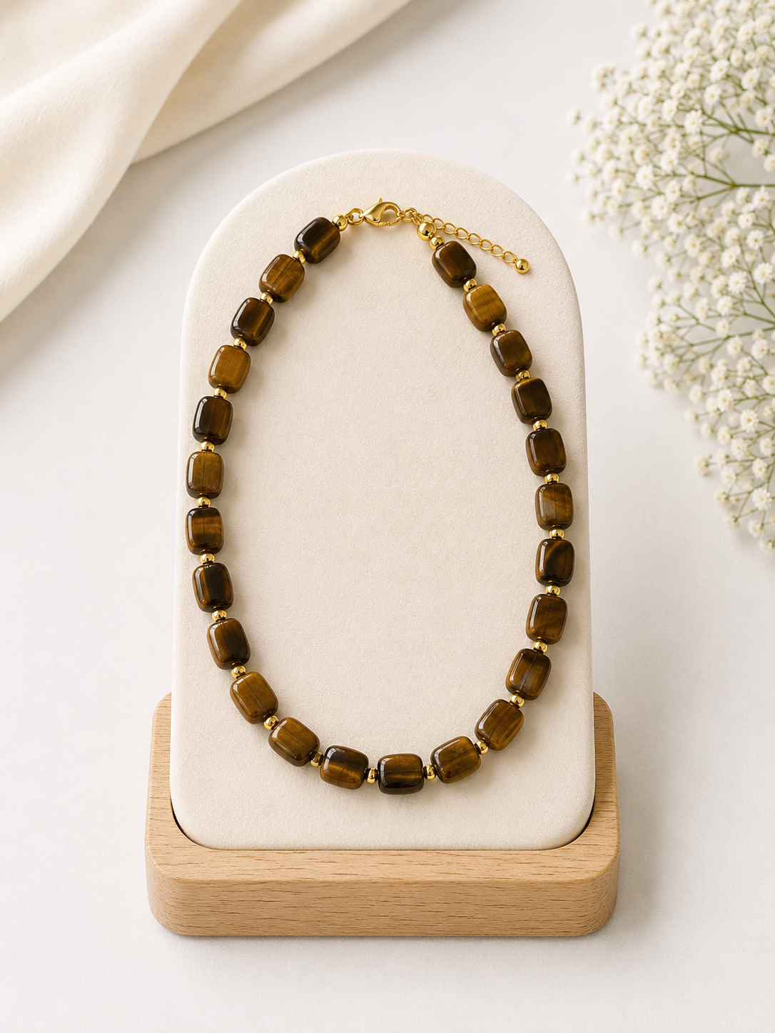 Brown beaded necklace on a white stone and wooden stand with a light background