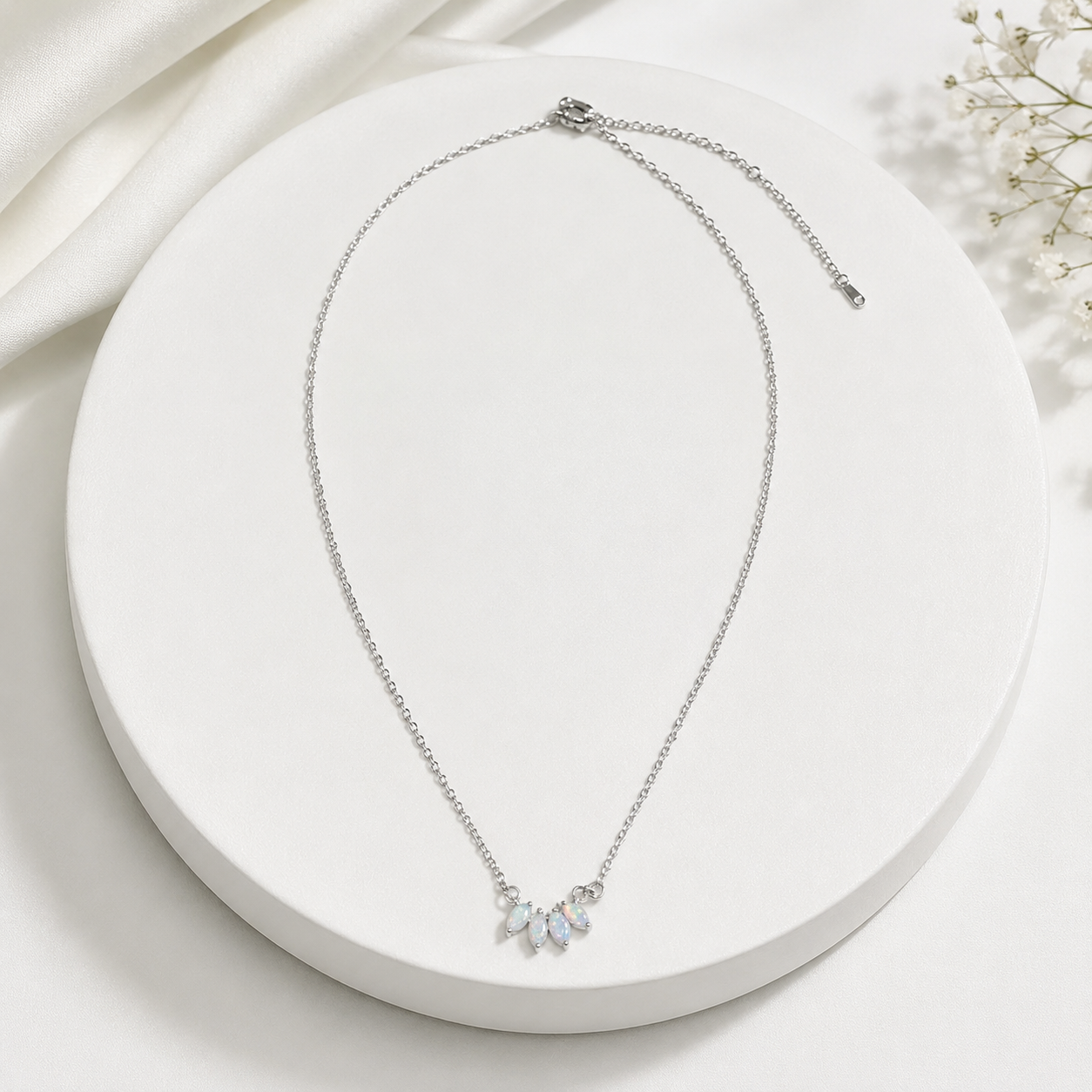 Silver necklace with small pendants on a white plate