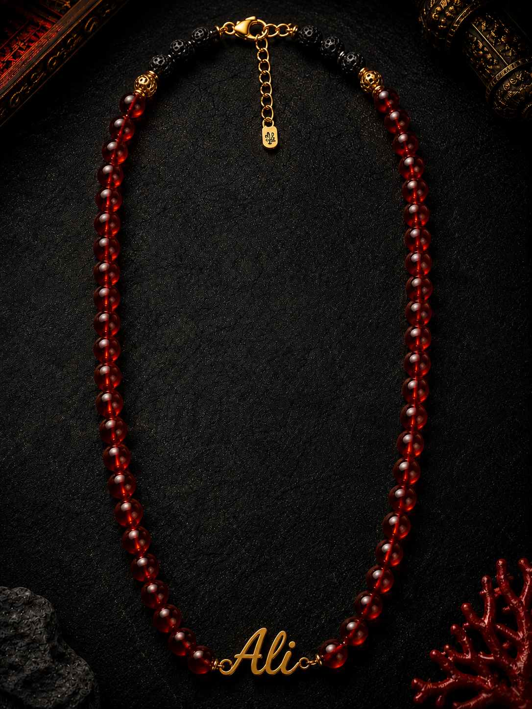 Red beaded necklace with 'Ali' engraving on a dark background