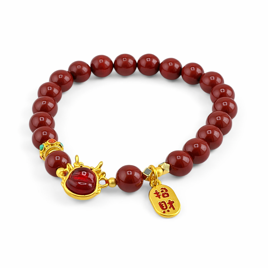 Bracelet with red beads and gold charms on a white background