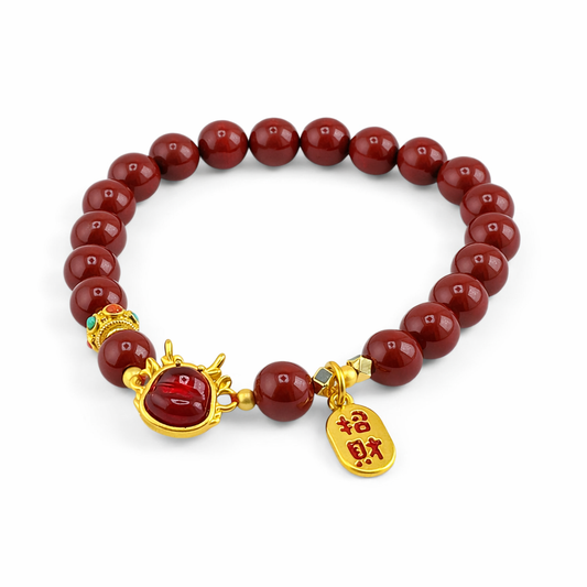 Bracelet with red beads and gold charms on a white background