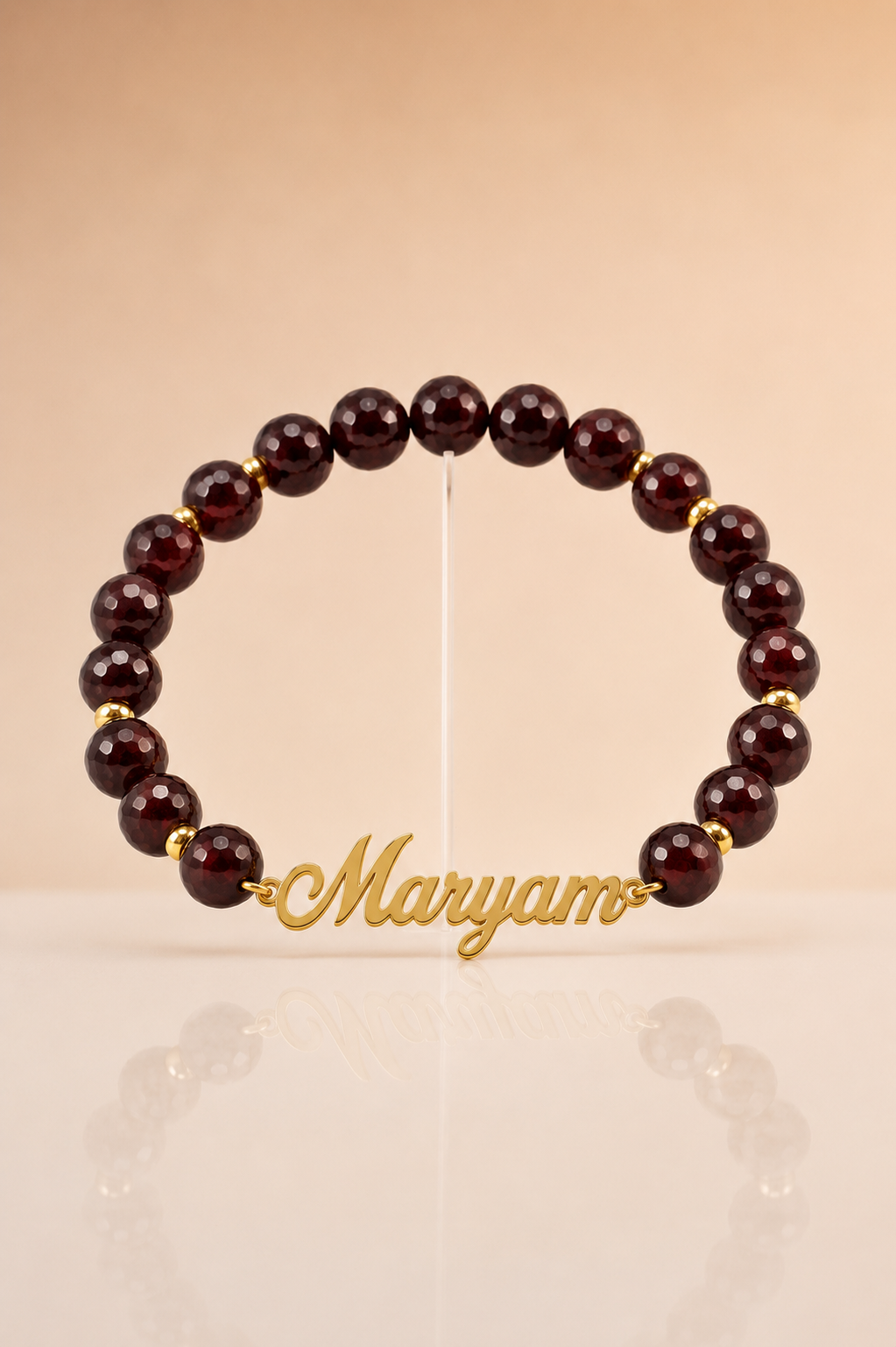 Beaded bracelet with 'Maryam' charm on a beige background