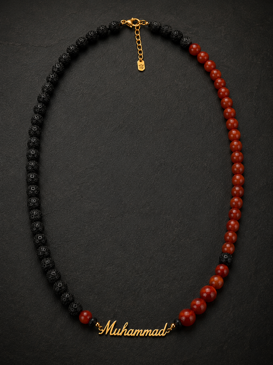 Necklace with black and red beads and a gold 'Muhammad' charm on a dark background