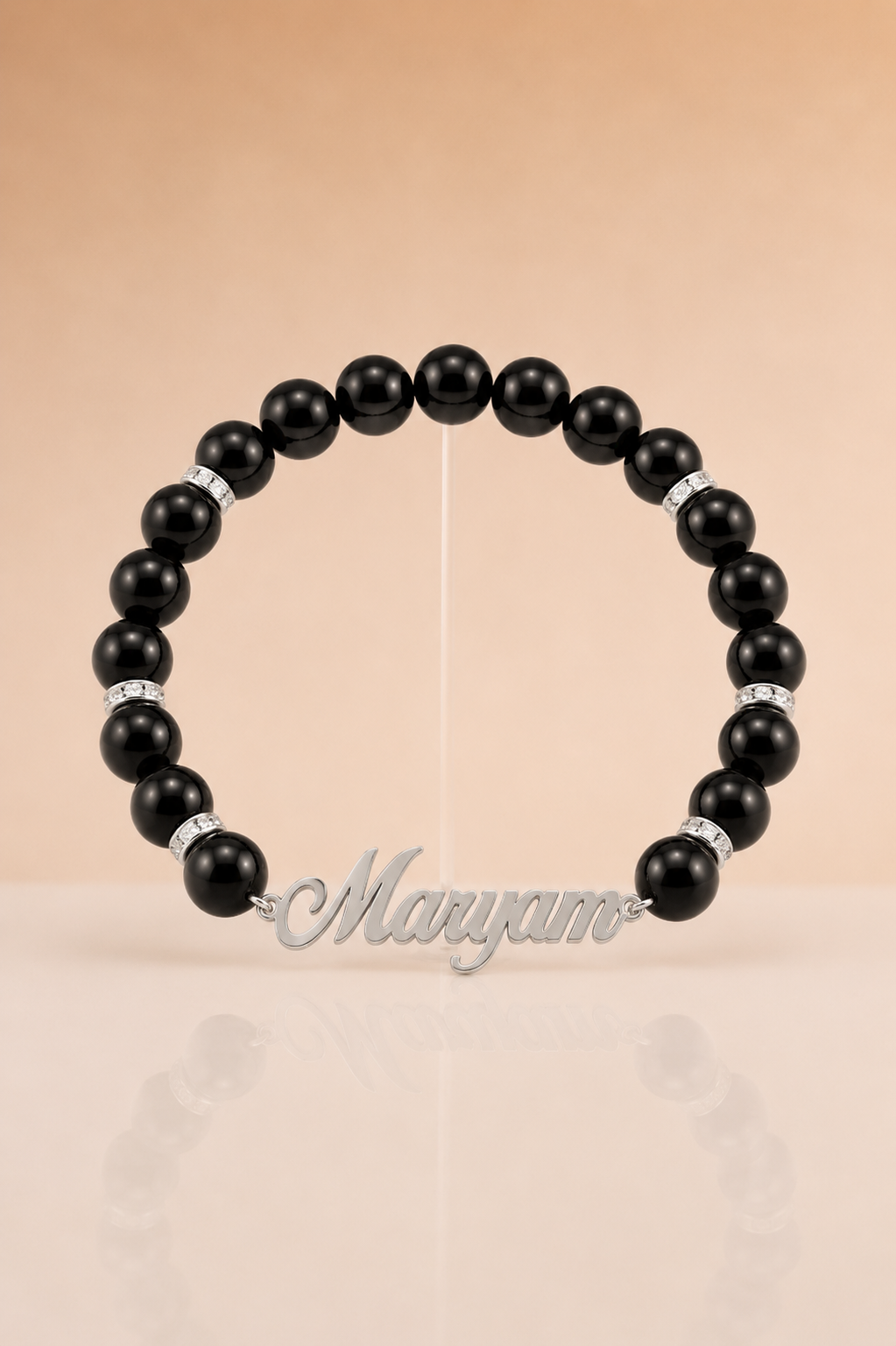 Black beaded bracelet with silver accents on a beige background, branded 'Maryam'.