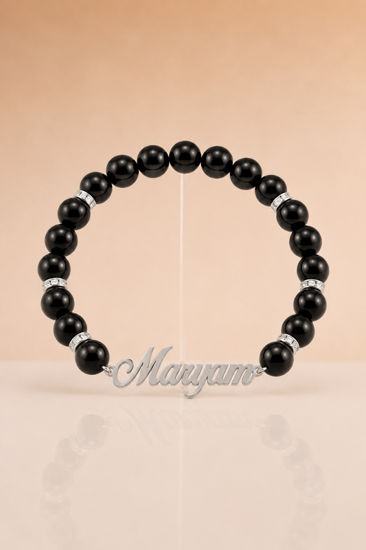 Black beaded bracelet with silver accents on a beige background, branded 'Maryam'.