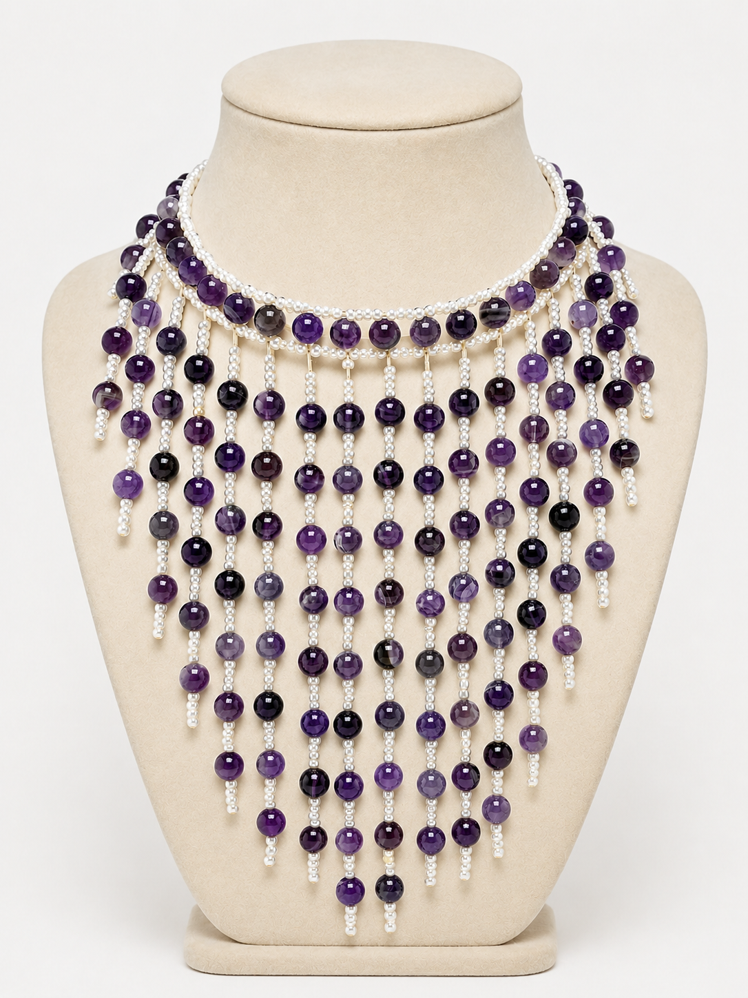 Necklace with purple and white beads on a mannequin bust against a white background