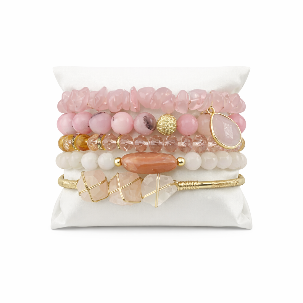 Set of pink and gold beaded bracelets on a white stand