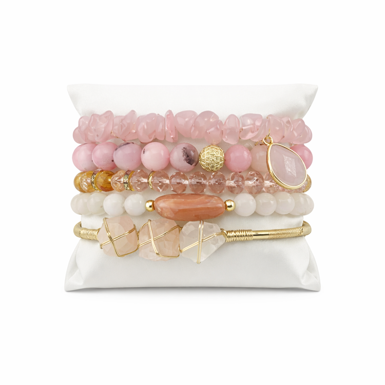 Set of pink and gold beaded bracelets on a white stand