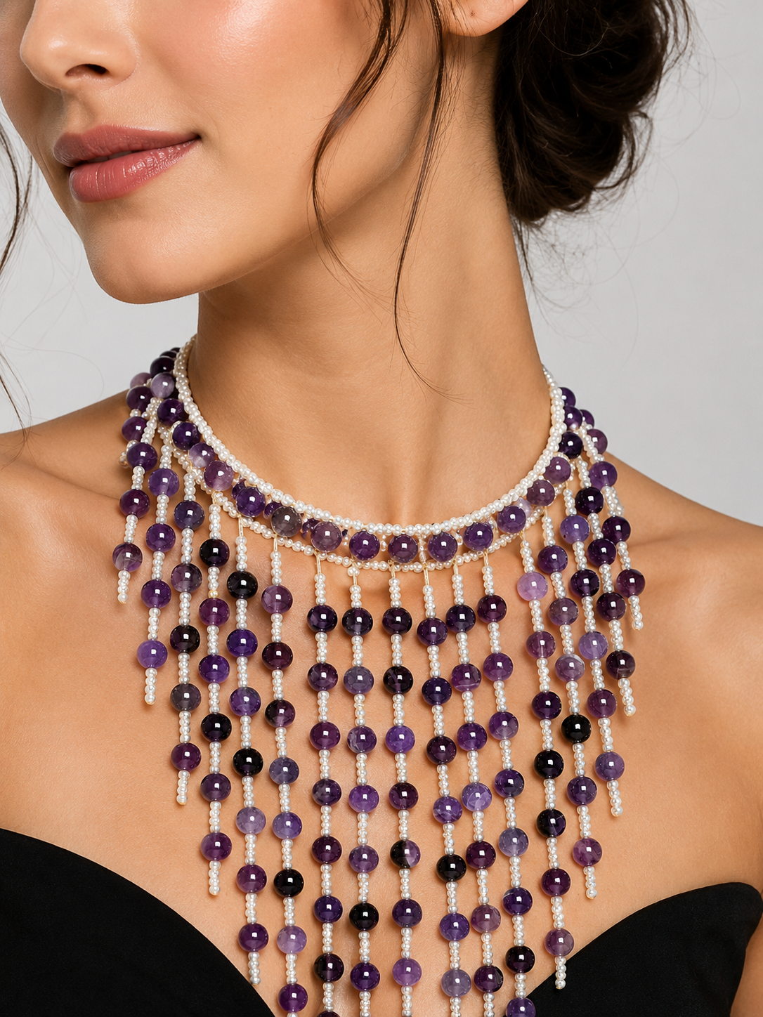 Woman wearing a beaded necklace with purple and black beads on a neutral background