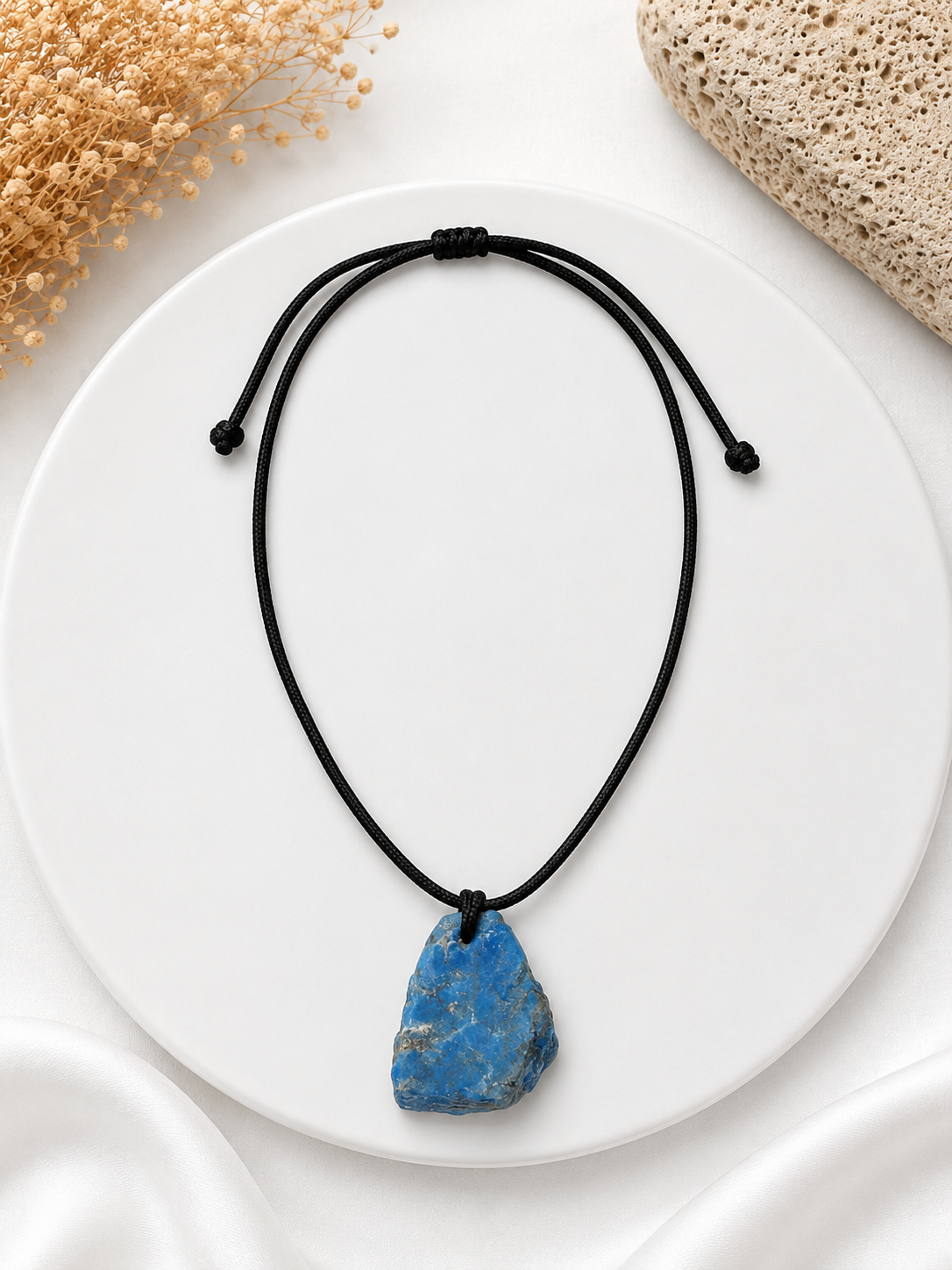 Necklace with a blue stone pendant on a white plate