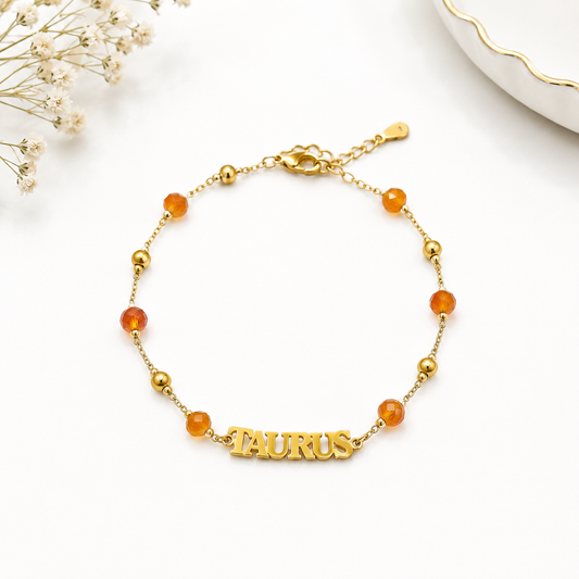 Gold bracelet with 'Taurus' charm on a white background