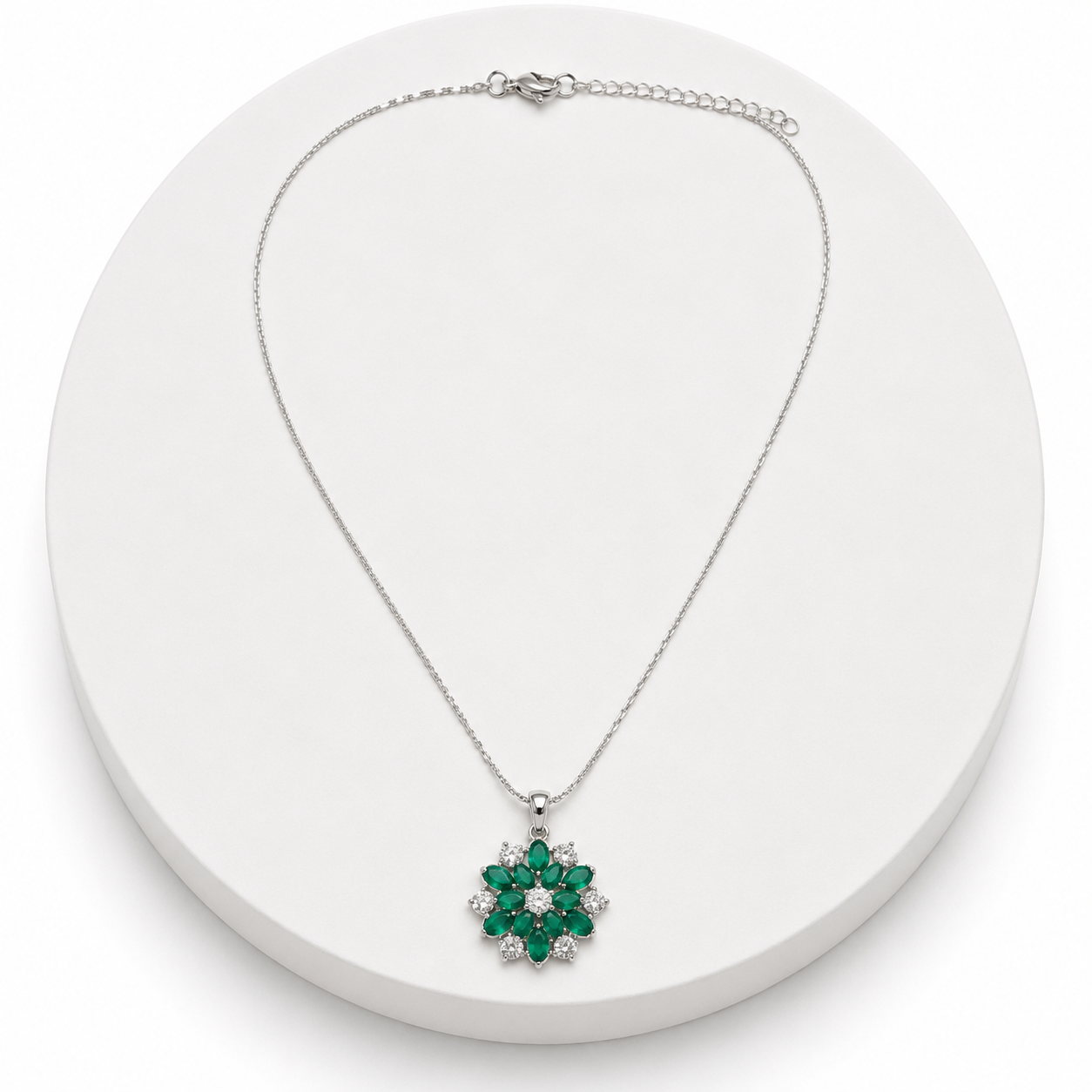 Silver necklace with a green gemstone pendant on a white background