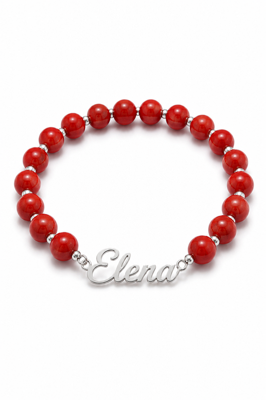 Red beaded bracelet with a silver nameplate on a white background