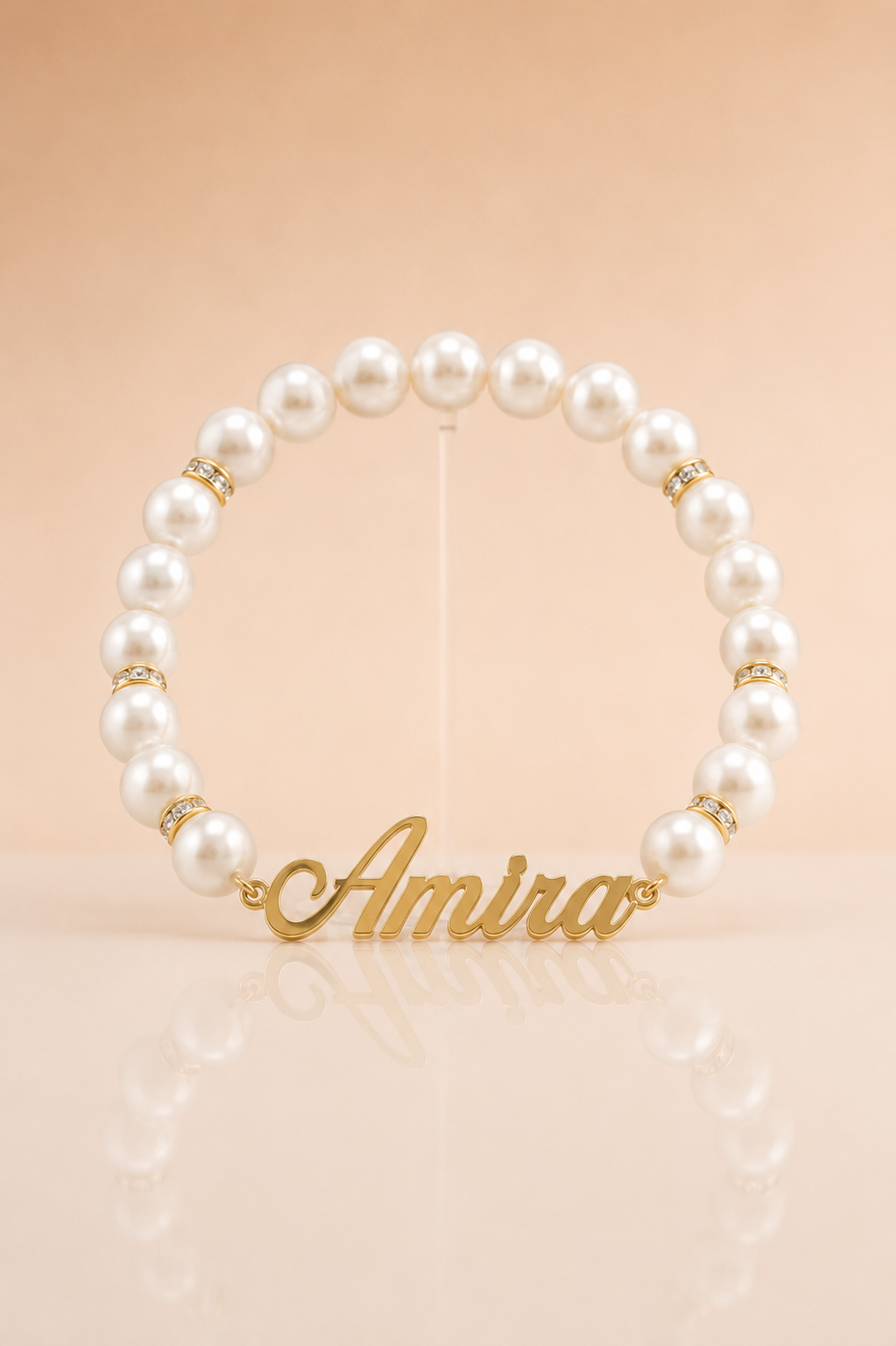 Pearl bracelet with gold name charm 'Amira' on a beige background