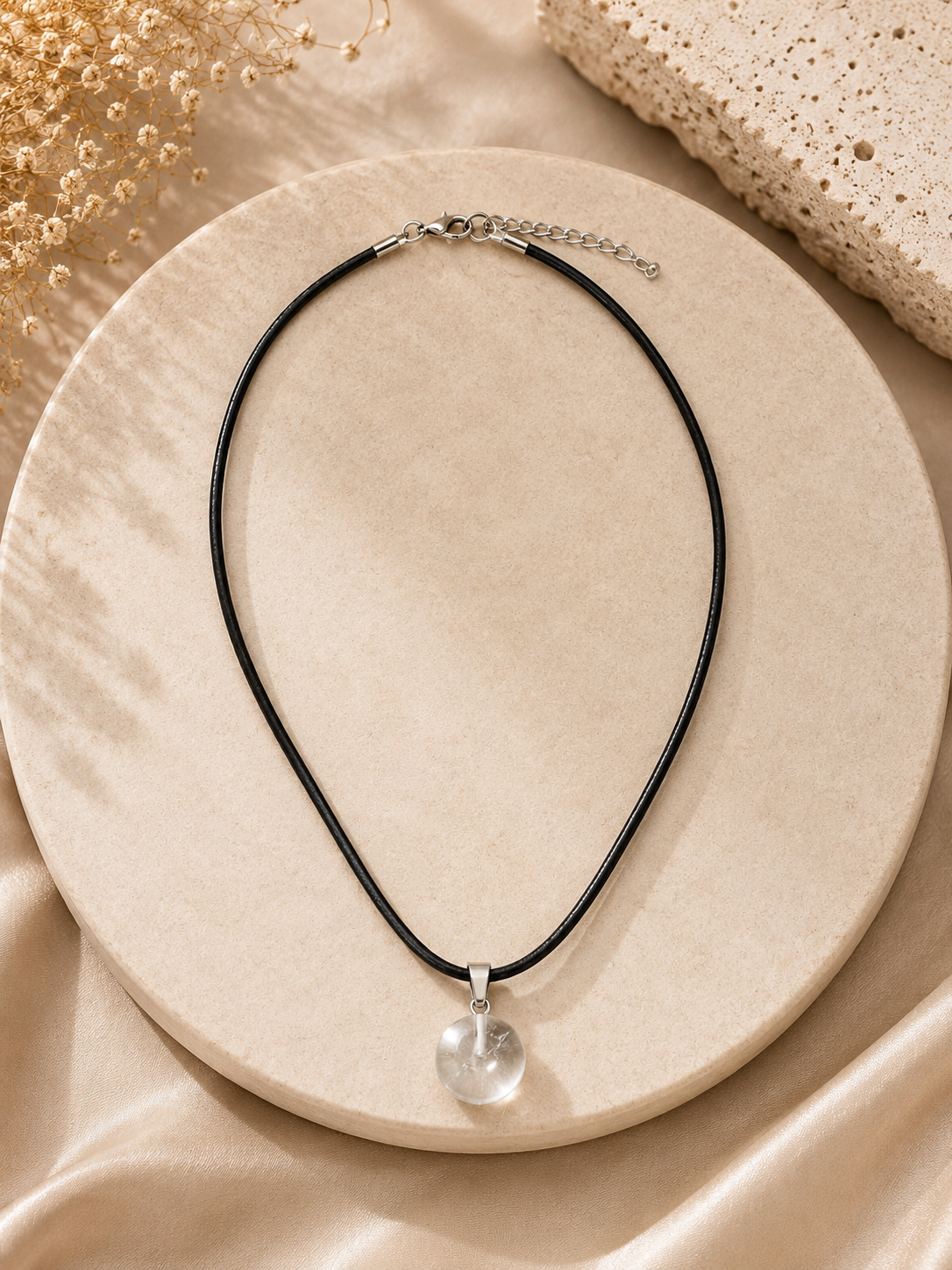 Necklace with a clear pendant on a beige surface