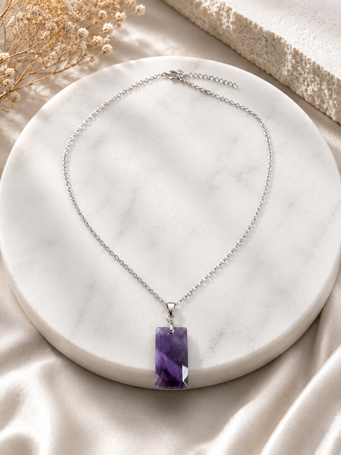 Necklace with a purple pendant on a marble surface