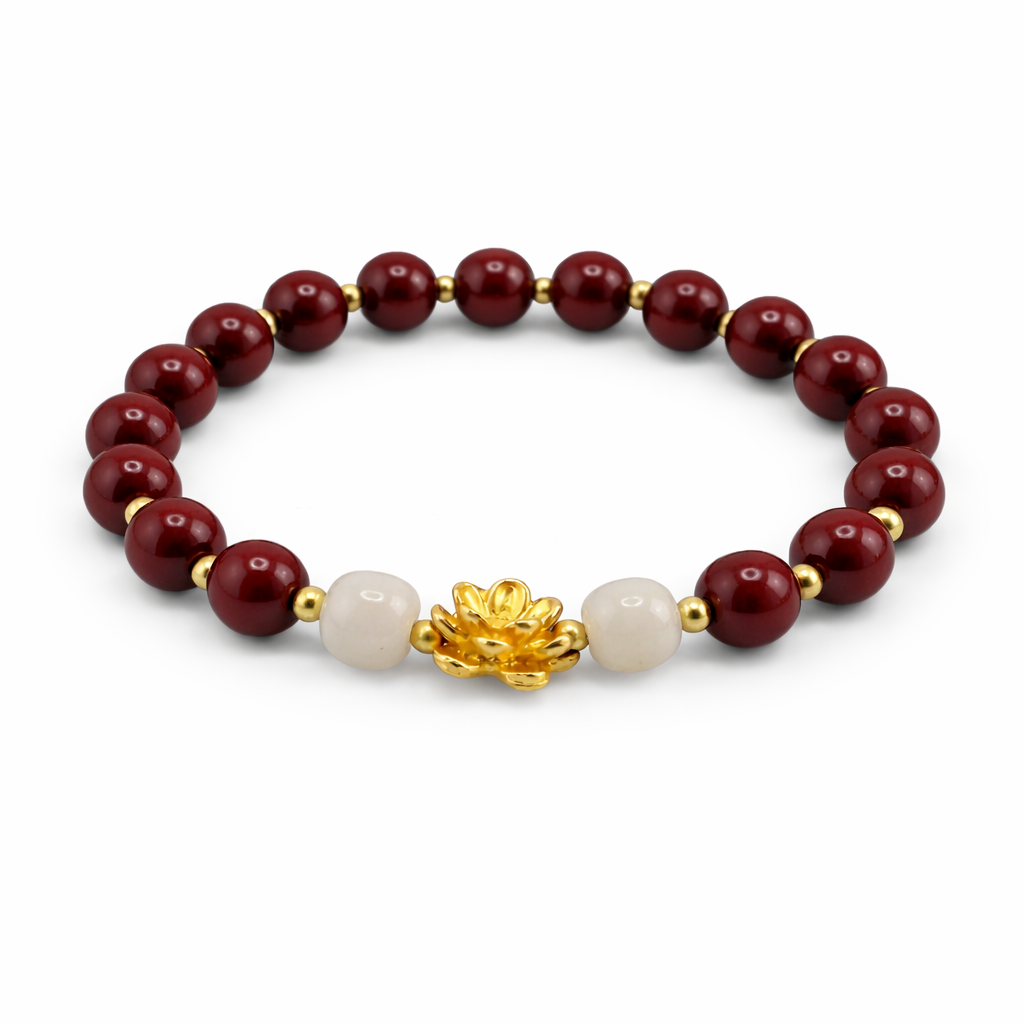Bracelet with red beads, white pearl, and gold lotus charm on a white background