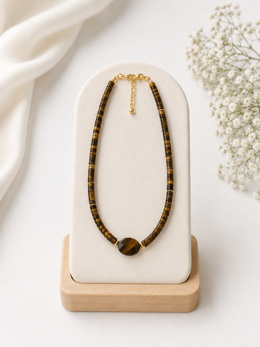 Necklace with tiger's eye beads on a white stand with a light background