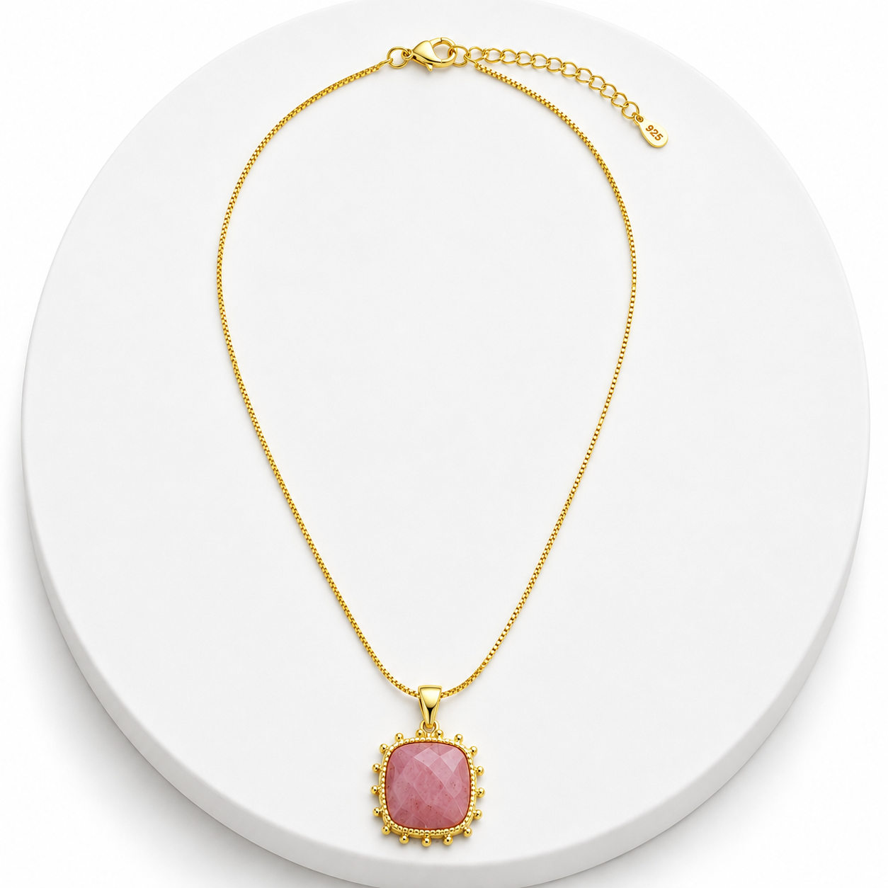Gold necklace with a pink pendant on a white background