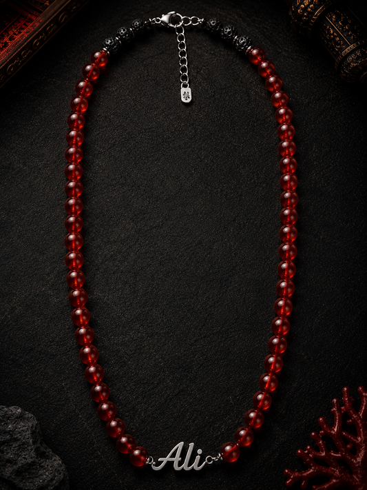 Red beaded necklace on a dark surface with 'Ali' branding.
