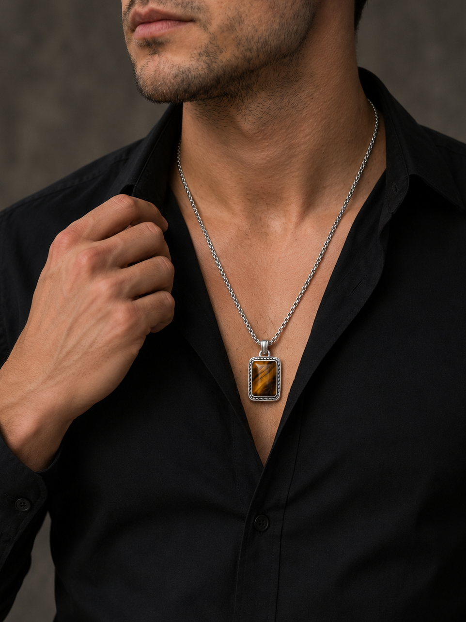 Man wearing a black shirt with a silver necklace featuring a prominent pendant.
