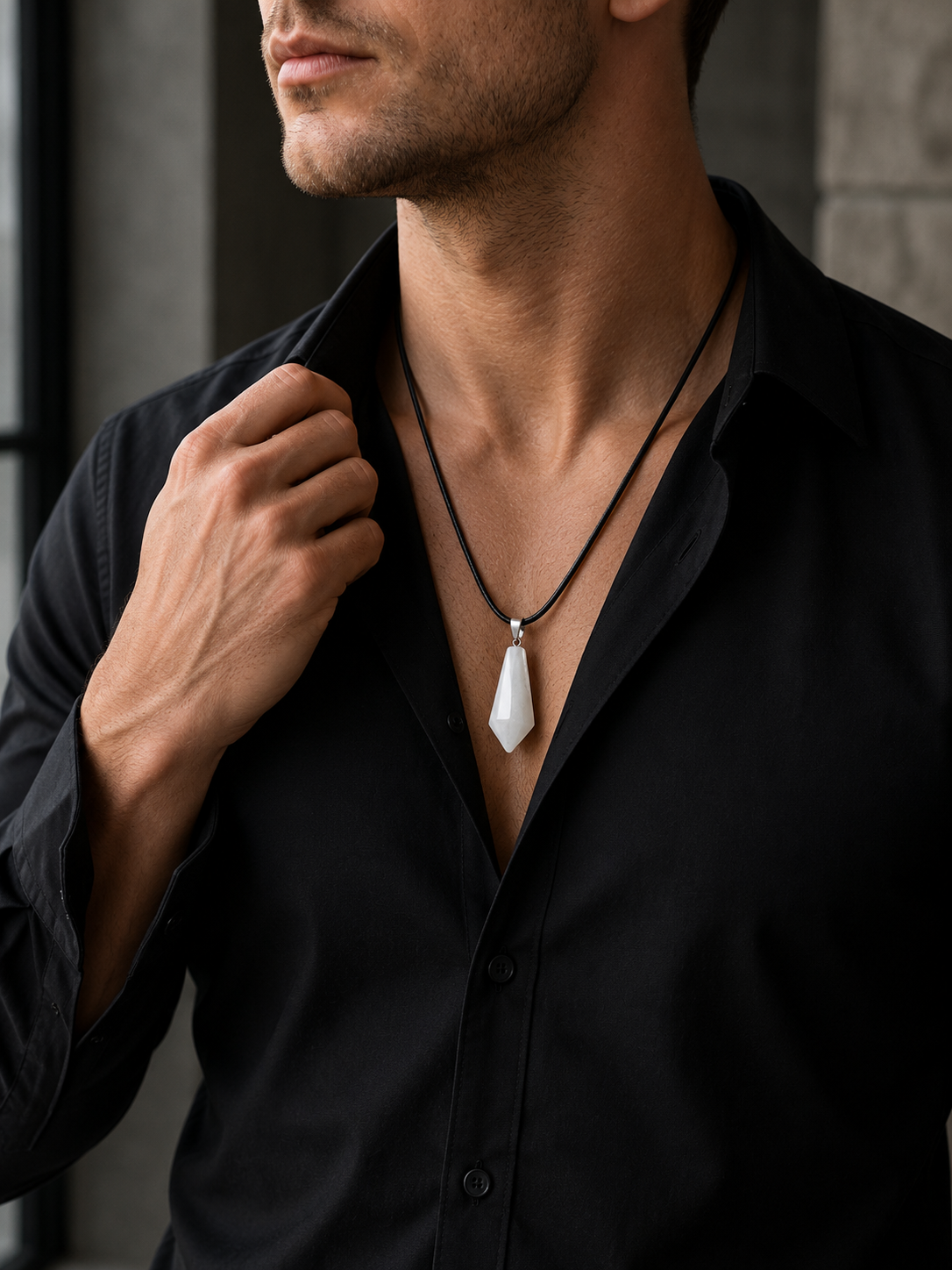 Man wearing a black shirt with a necklace featuring a white pendant.