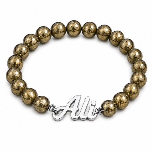 Bracelet with gold beads and a silver 'Ali' charm on a white background