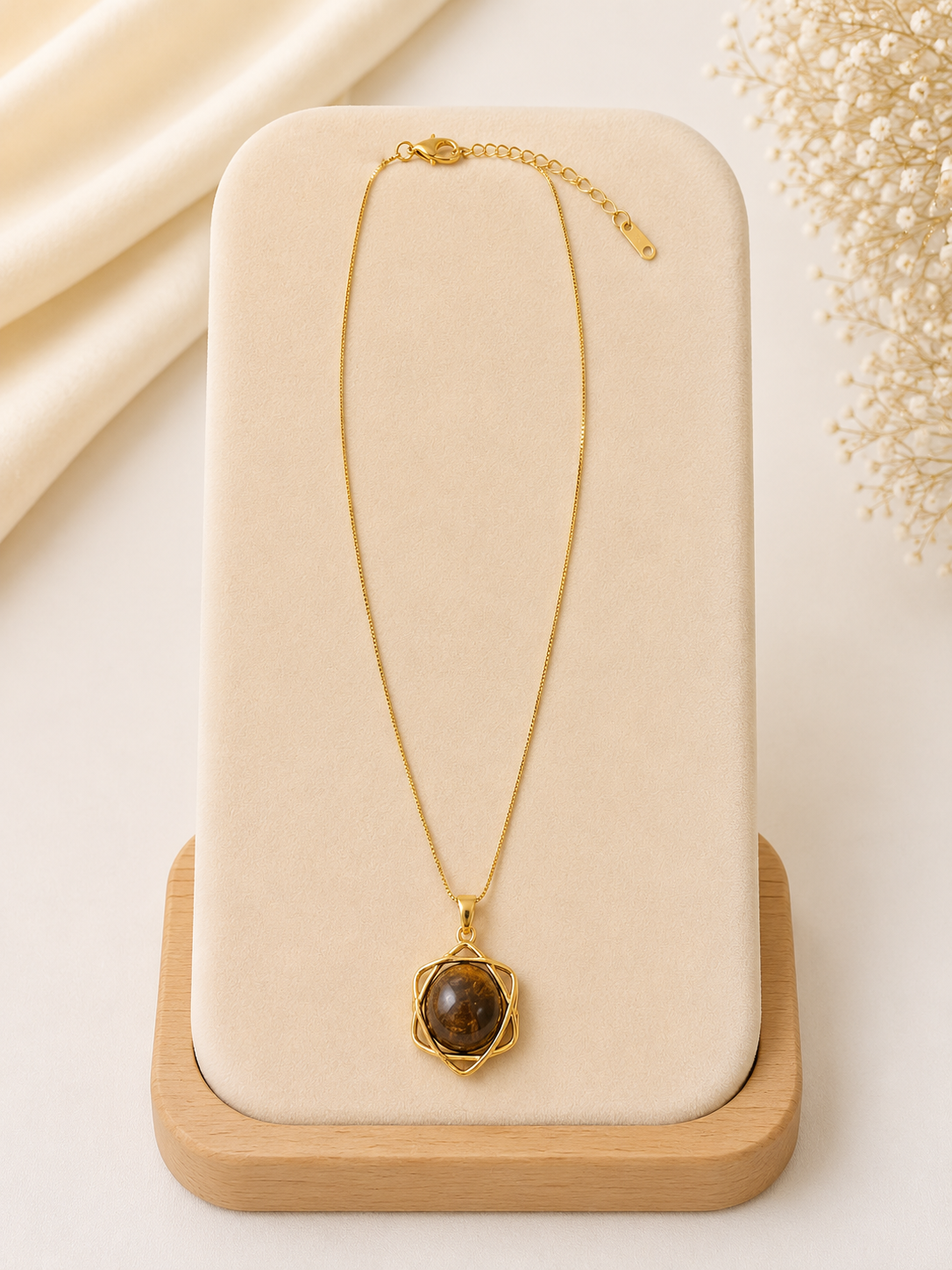 Gold necklace with a brown pendant on a beige stand