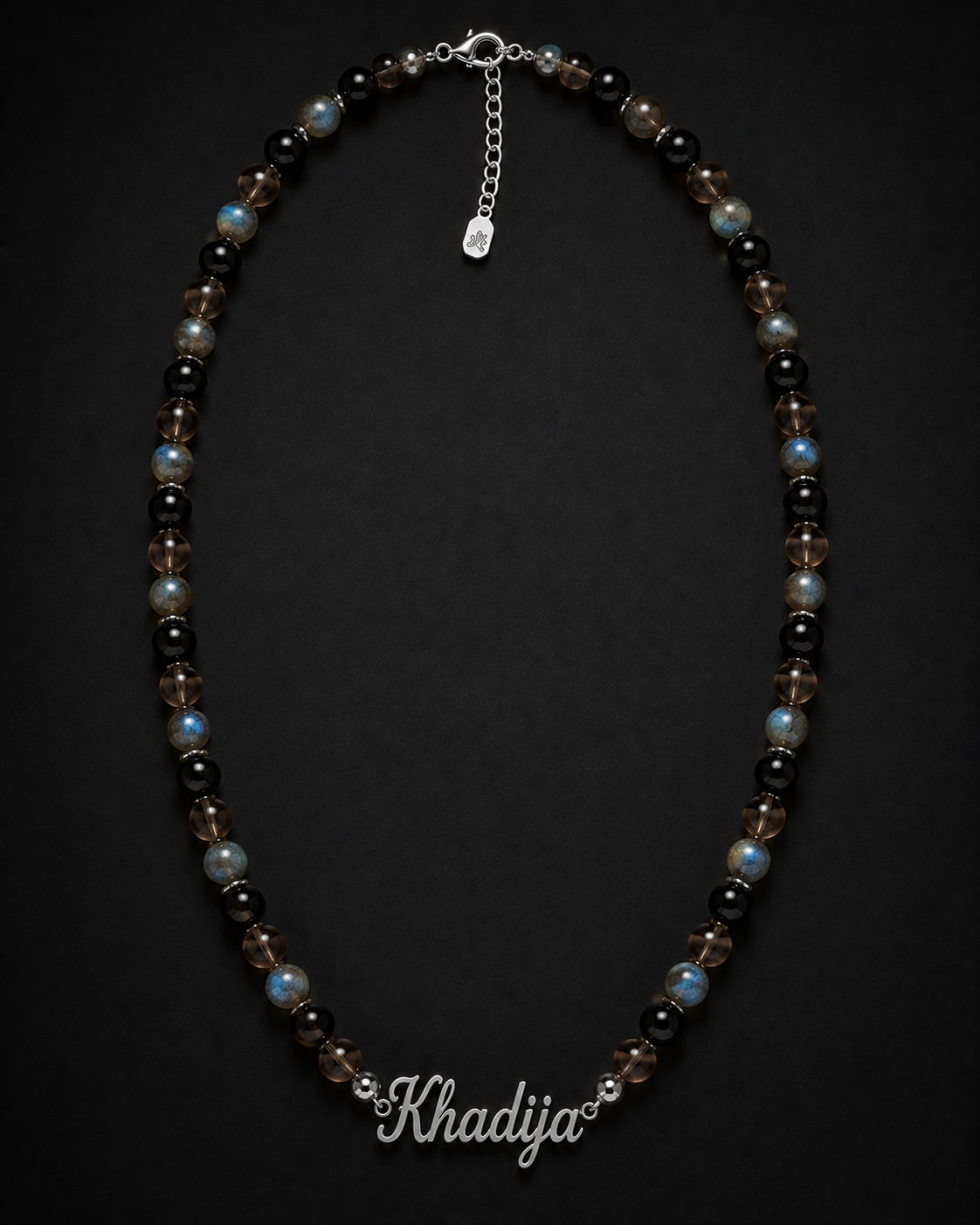 Necklace with beads on a dark background, branded 'Khadija'.