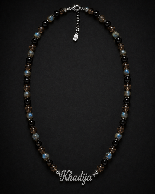 Necklace with beads on a dark background, branded 'Khadija'.