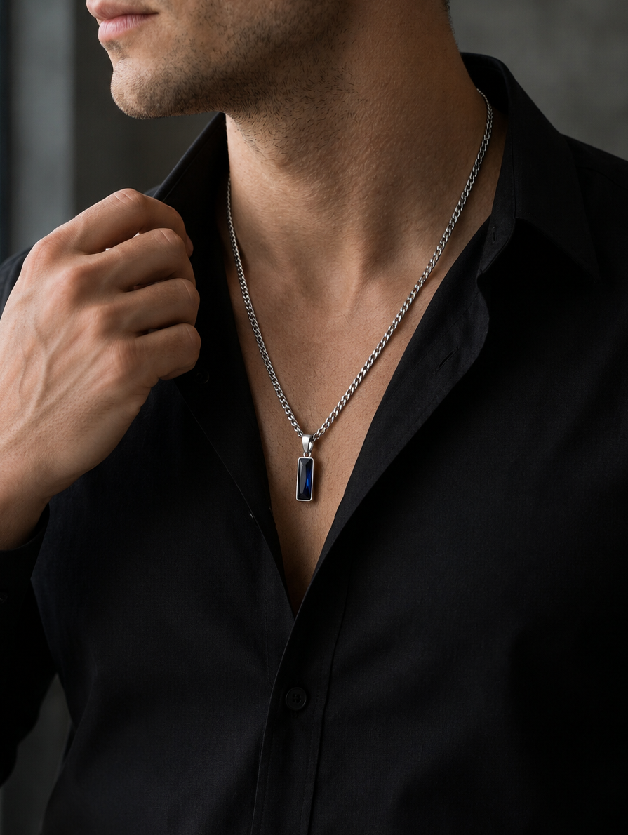 Man wearing a black shirt with a silver necklace featuring a blue gemstone.