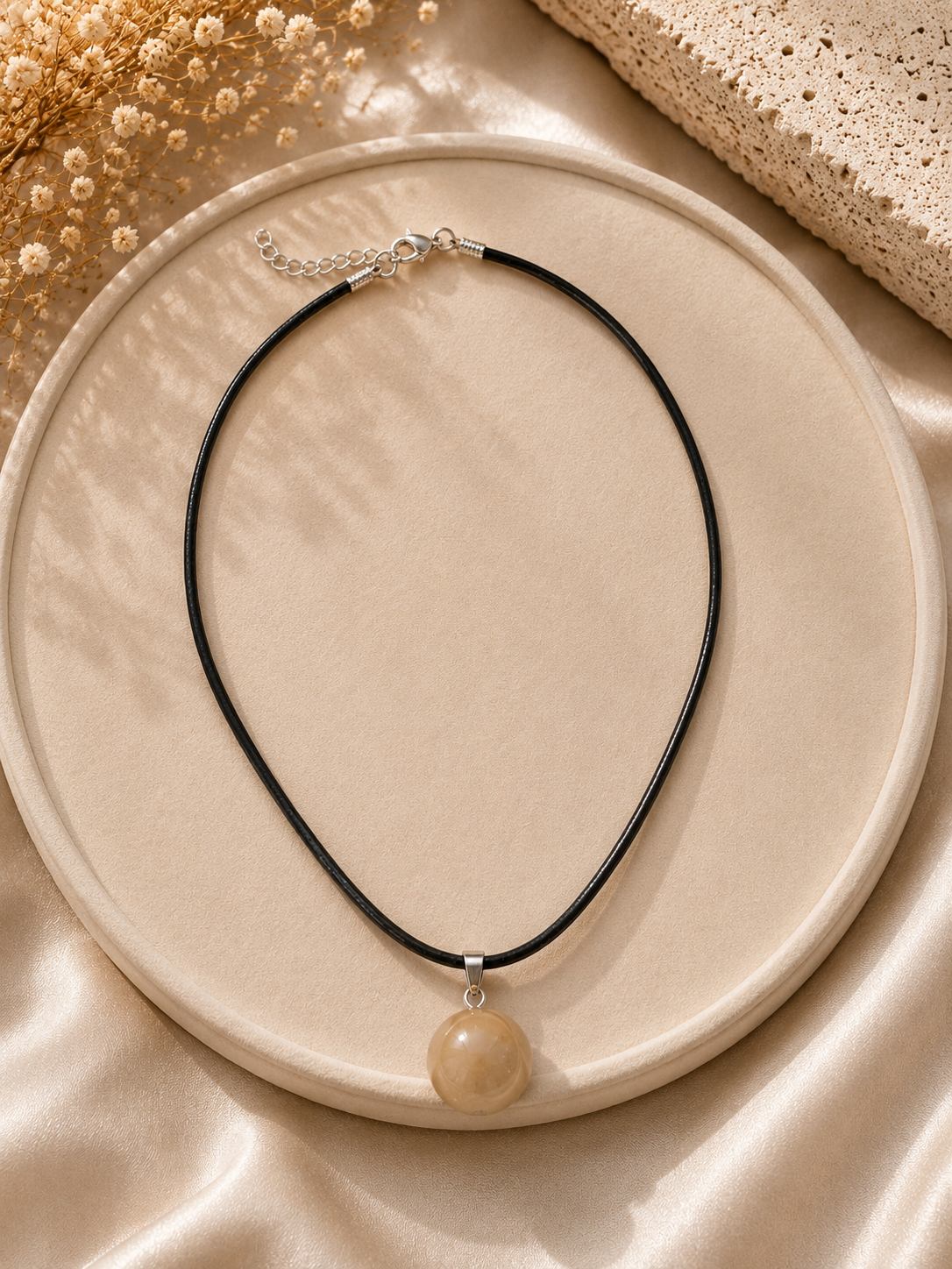 Necklace with a round pendant on a beige plate