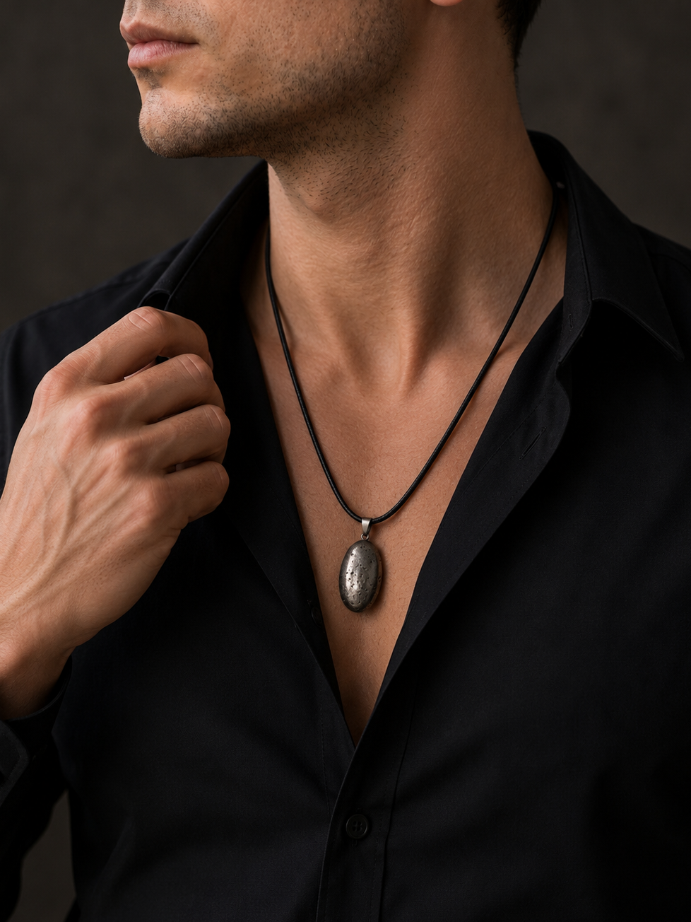 Man wearing a black shirt with a necklace against a dark background