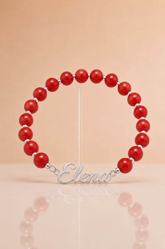 Red beaded bracelet with a silver nameplate on a beige background