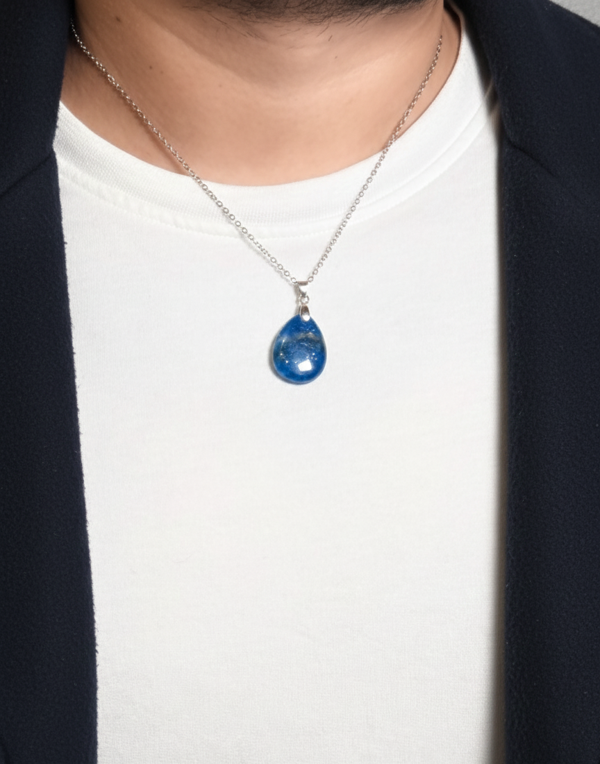 Person wearing a necklace with a blue pendant on a white background