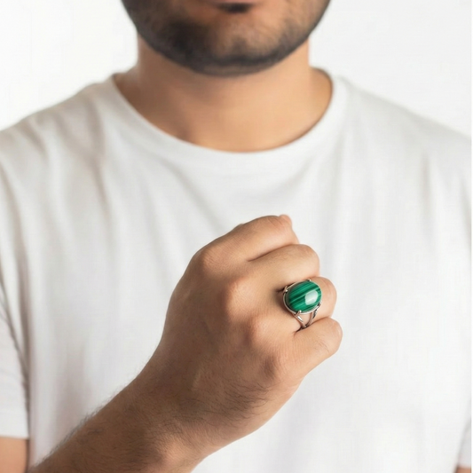 Man wearing a white shirt and a green ring on a plain background