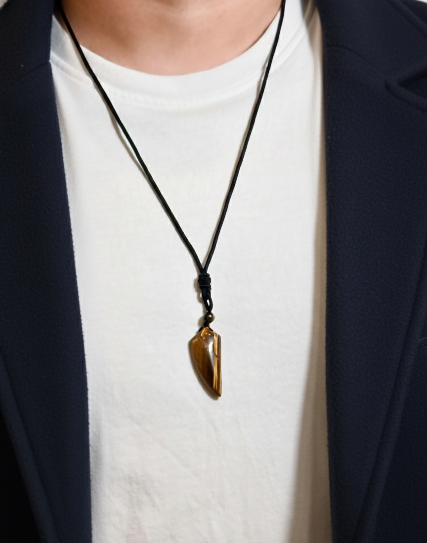 Person wearing a necklace with a pendant, dressed in a white shirt and dark jacket.