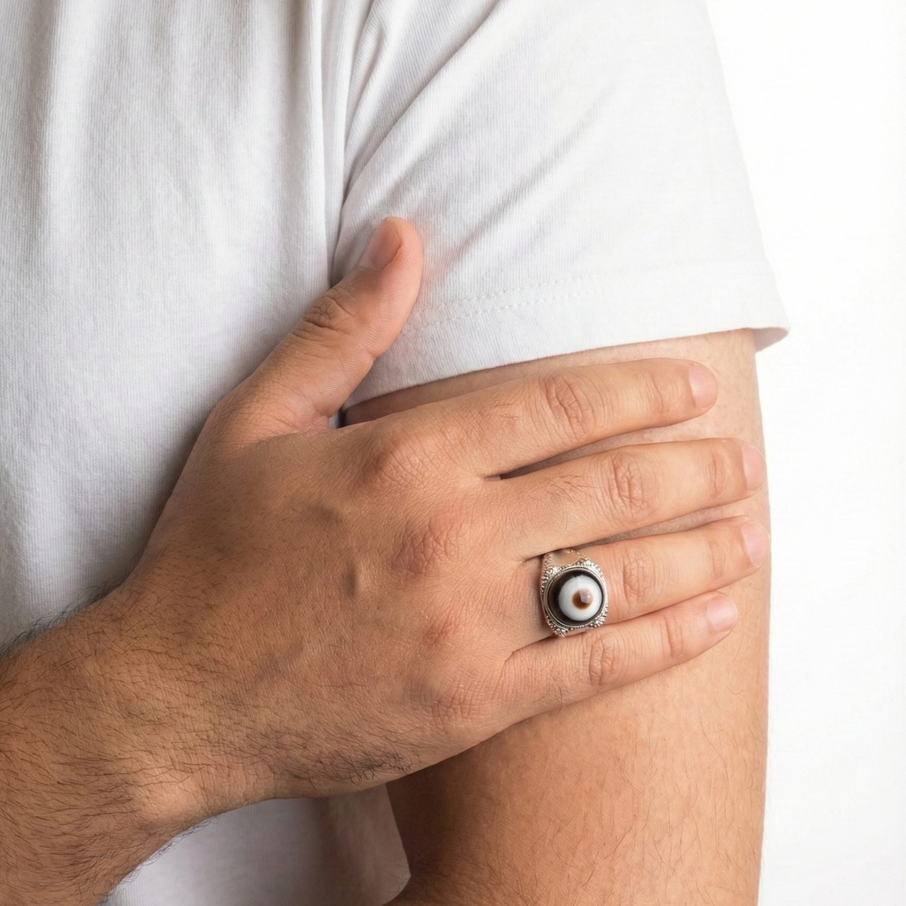 Hand with a ring on a person wearing a white shirt against a white background