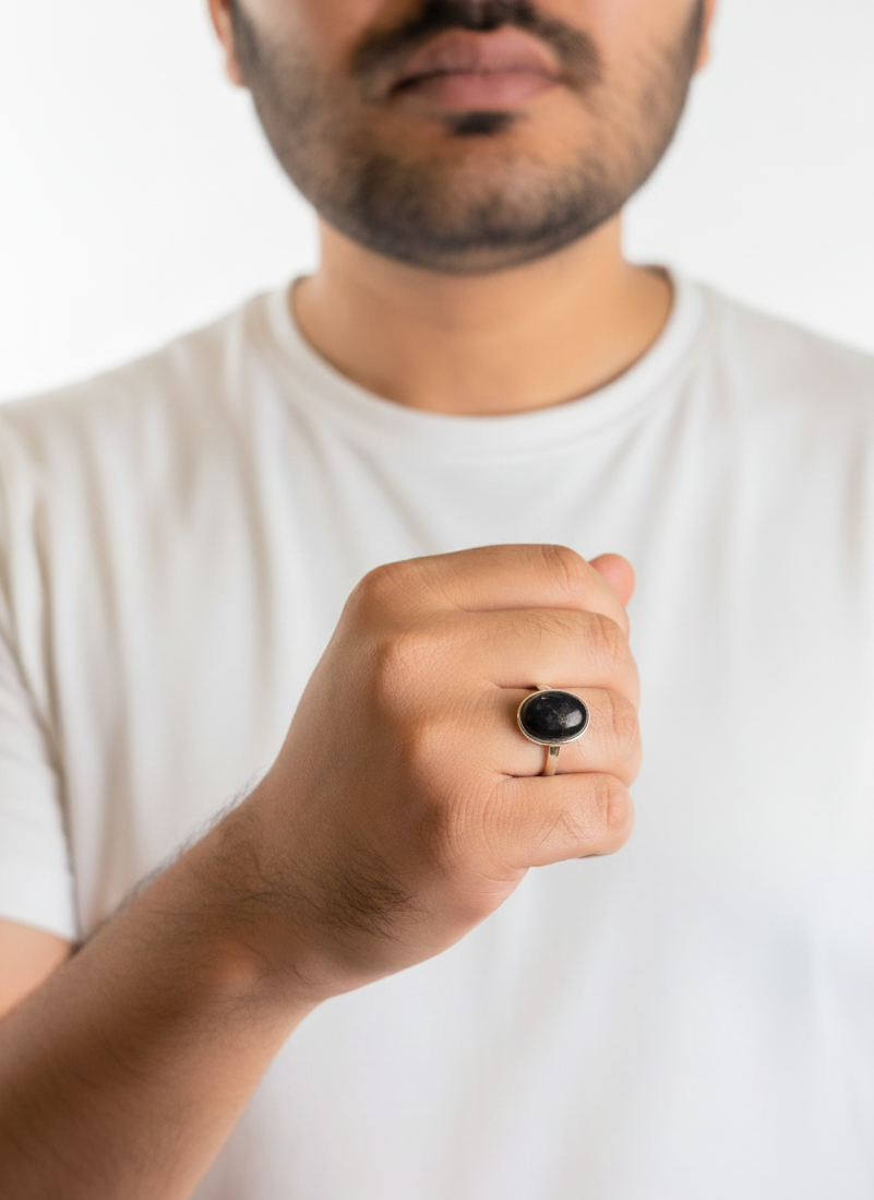 Man wearing a white t-shirt with a black ring on his finger against a white background