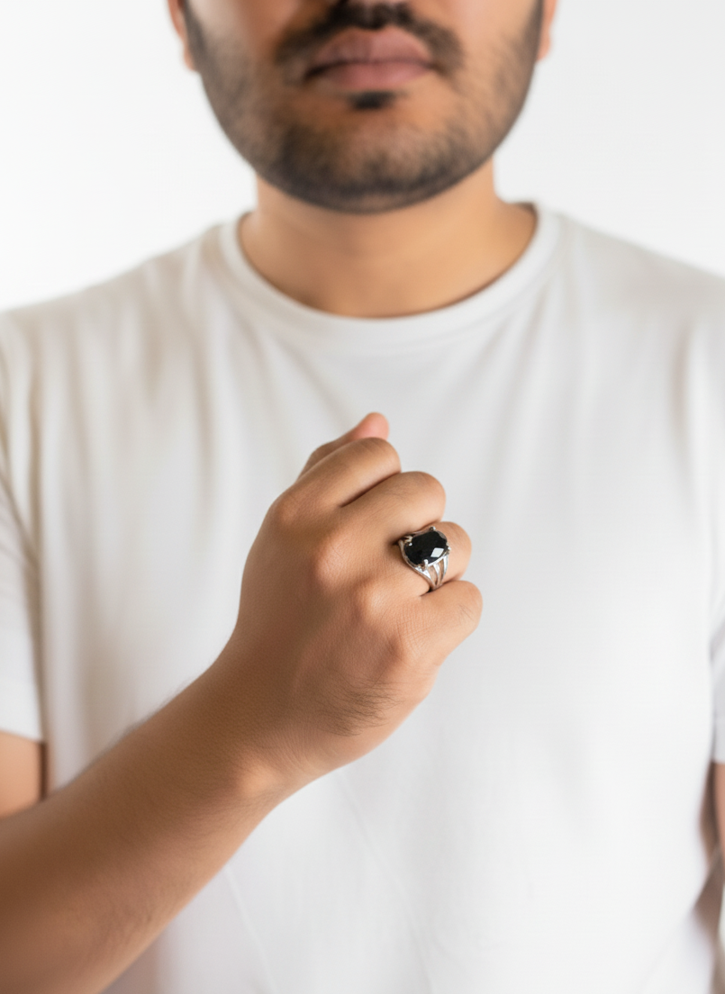 Man wearing a white t-shirt with a close-up of his hand holding a black ring.