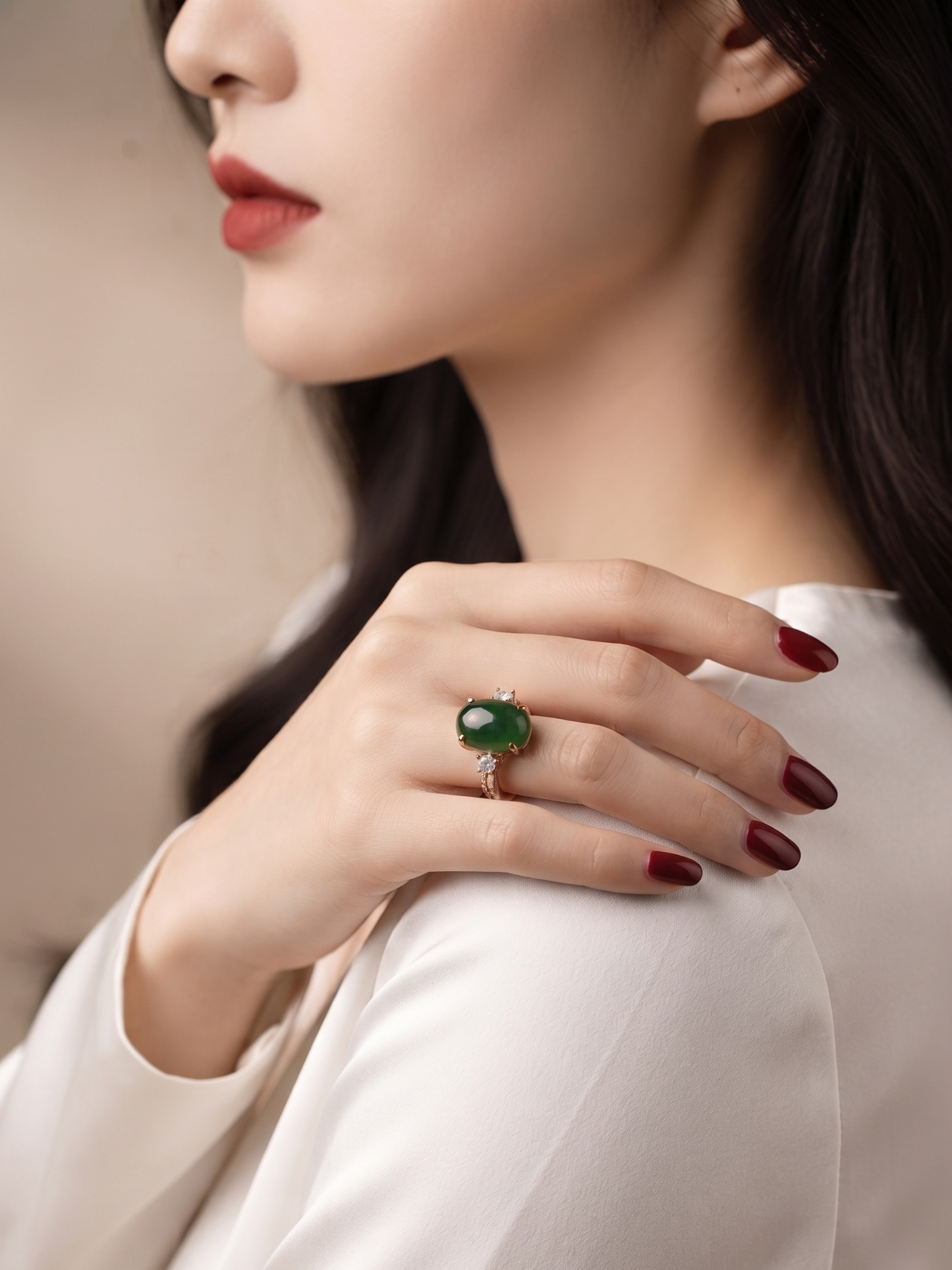 A close-up lifestyle shot of a woman wearing a gold ring with a green oval gemstone, resting her hand on her shoulder.