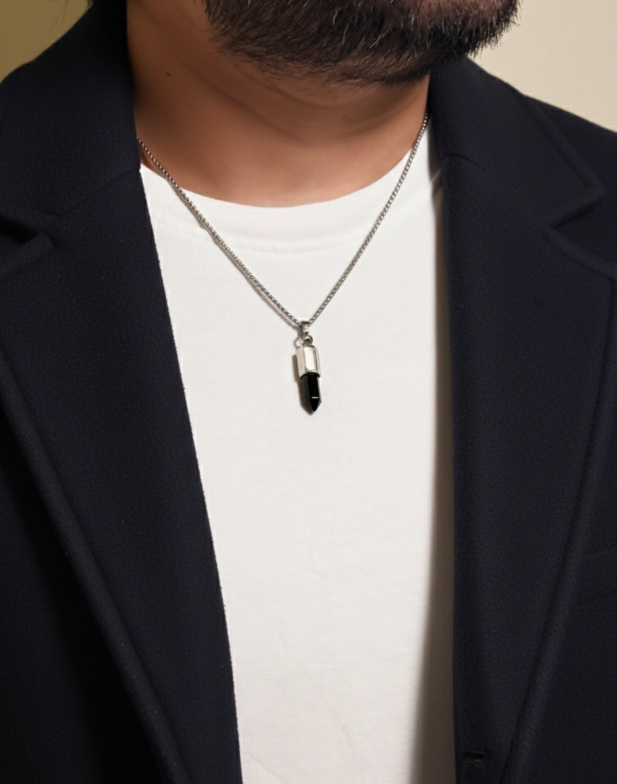 Person wearing a black pendant necklace with a plain background